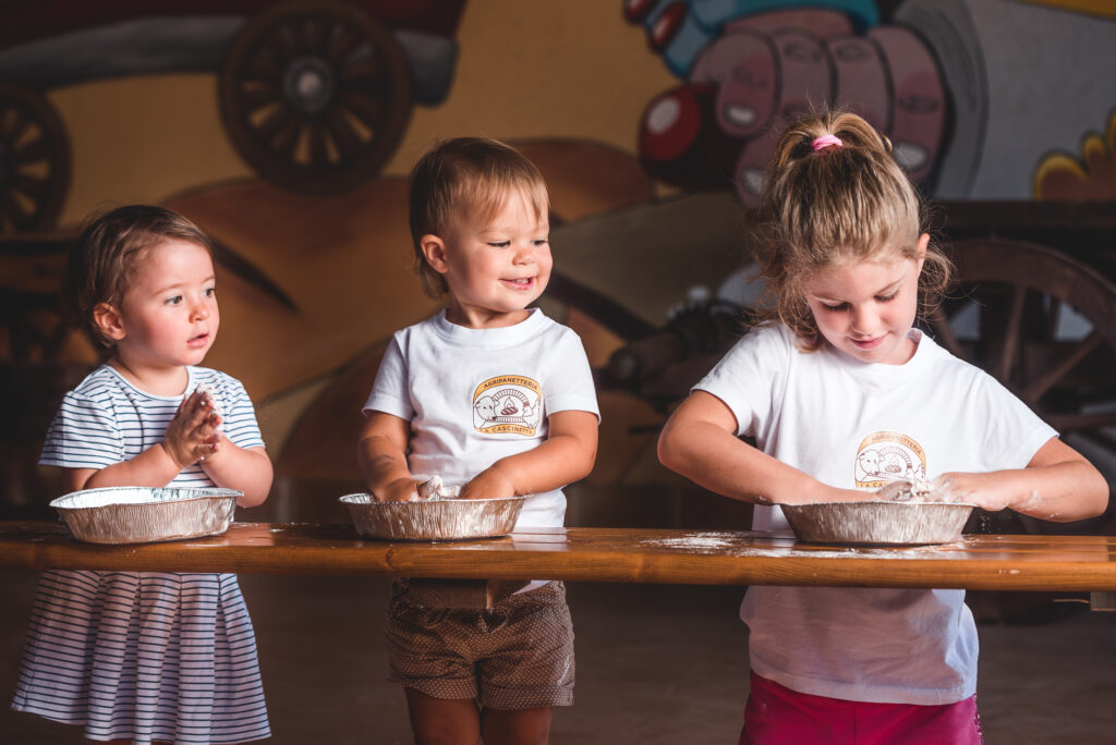 Tre bambini che cucinano insieme durante un laboratorio nella fattoria didattica La Cascinetta a Villanova d’Asti